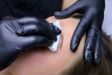 close-up of the master's hand in black gloves removes the compositions for laminating eyebrows with...