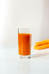 Healthy drink: glass of fresh carrot juice and fresh carrots isolated on white. Vertical plane. Copy space.