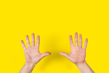 Manos de hombre mostrando las palmas abiertas sobre un fondo amarillo brillante liso y aislado. Vista de frente y de cerca. Copy space
