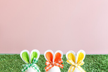 Easter decoration on pink background, colorful easter eggs with bunny ears.