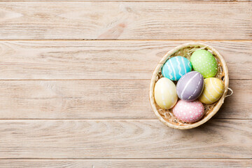 Multi colors Easter eggs in the woven basket on colored background . Pastel color Easter eggs. holiday concept with copy space