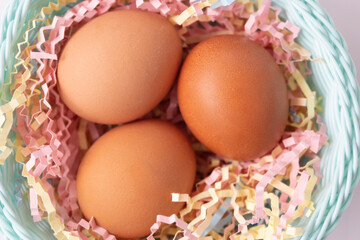 Large brown chicken eggs in a smart basket. Multi-colored tinsel. Easter concept