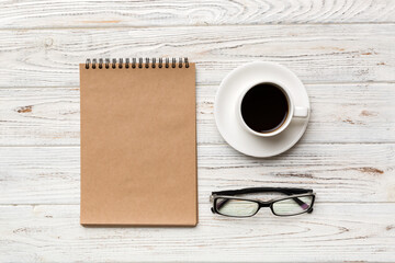 Modern office desk table with notebook and other supplies with cup of coffee. Blank notebook page for you design. Top view, flat lay