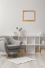Grey armchair with shelving unit near light wall