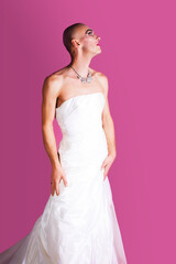 Profile of gender fluid male model wearing white wedding dress looking up, on pink background