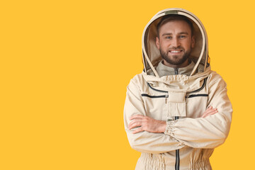 Male beekeeper in protective suit on yellow background - obrazy, fototapety, plakaty