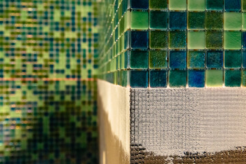 Wall covered with green mosaic ceramic tiles. Bathroom, sauna, spa room in process of renovation.