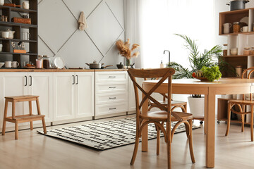 Interior of modern kitchen with white counters, shelving units and dining table