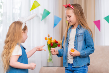 little girls with Easter eggs play the game stone paper scissors