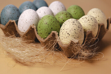 colored easter eggs in egg pulp tray on yellow background, copy space	