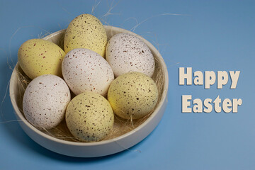 upper view of yellow easter eggs in white bowl on blue background, copy space with text	