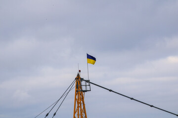 Ukrainian flag mounted on a construction crane flying in the wind against the blue sky
