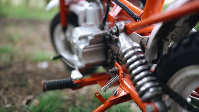 Close-up of the lower part of a sports moped. In the frame there is a footrest and an engine