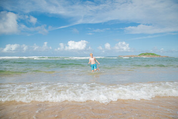 Boy swimming in crystal blue water at Park Beach in Coffs Harbour, NSW Australia