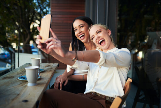 Coffee shop selfies are the best. Shot of two young women taking a selfie while sitting at a cafe.