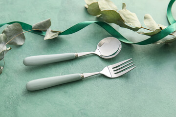 Elegant cutlery and eucalyptus leaves on green background