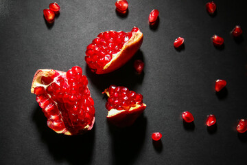 Tasty ripe pomegranate pieces on dark background