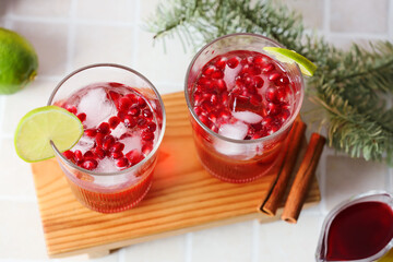 Glasses of tasty pomegranate cocktail on tile background