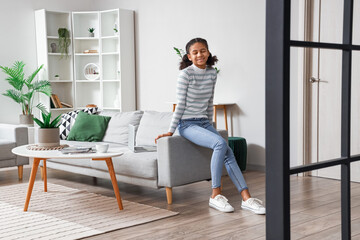 African-American teenage girl sitting on sofa at home