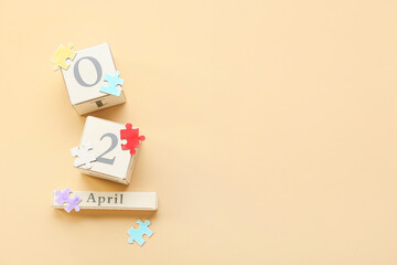 Cube calendar with date of World Autism Awareness Day and puzzle pieces on beige background