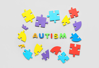 Naklejka premium Word AUTISM with puzzle pieces on light background