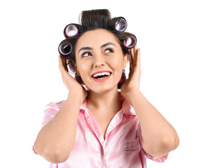 Fototapeta premium Happy young woman in pajamas and hair curlers on white background