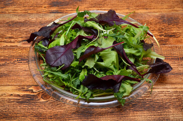 plate with fresh lettuce leaves on wooden background 
close-up 