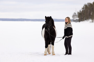 Icelandic horse and rider standing on lake ice. Black and white horse.