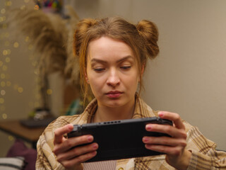 Girl gamer plays a video game on a gaming tablet. Close-up. Home furnishings. Modern technologies, youth culture, entertainment, leisure, communication, cyberspace.