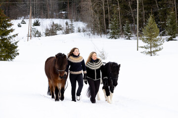 Two Icelandic horses with riders walking on uphill. Deep snow. Riders with Icelandic sweater.