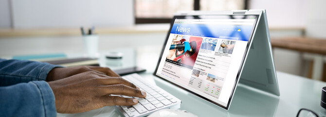 Reading Newspaper Article On Laptop