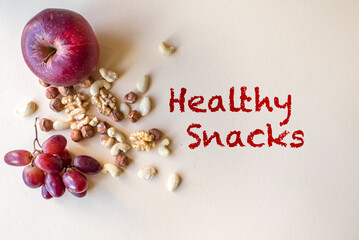 Healthy snacks, nuts, grapes and apples isolated on beige background