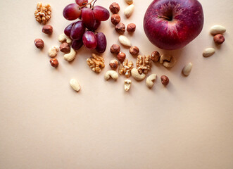 Healthy snacks, nuts, grapes and apples isolated on beige background