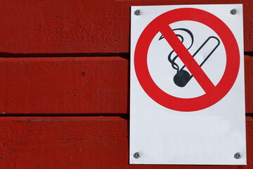 A non smoking sign at a red wall. No text. Copy space for your design.