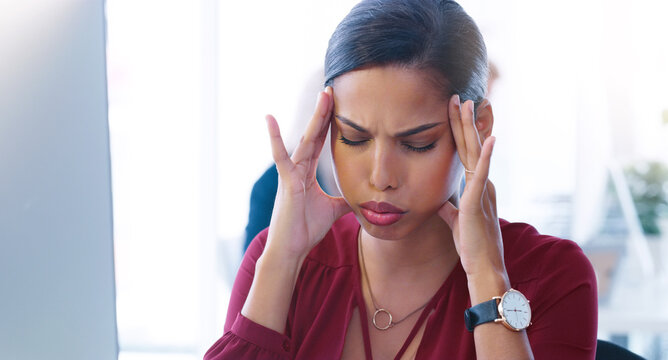My brain is going to explode. Cropped shot of a stressed young businesswoman seated at her desk while suffering from a headache in the office. - Powered by Adobe