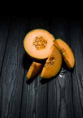 sweet melon on a dark background small delicious beautiful melon, both whole and in pieces and folded for eating