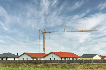Fototapeta na wymiar A rural housing estate with a crane nearby. Contruction site at a residential estate