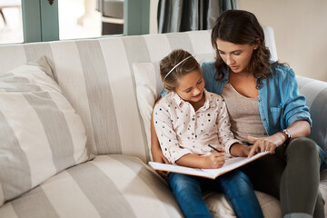 Learning with love. Shot of a young woman helping her adorable daughter with her homework at home.