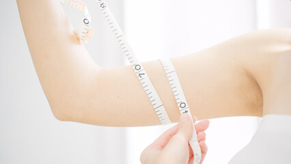腕のサイズをメジャーで測る女性　ビューティーイメージ