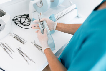 Dentist assistant sterilizing and packing dentist equipment in plastic sterilization pouches - obrazy, fototapety, plakaty