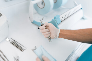 Dentist assistant sterilizing and packing dentist equipment in plastic sterilization pouches