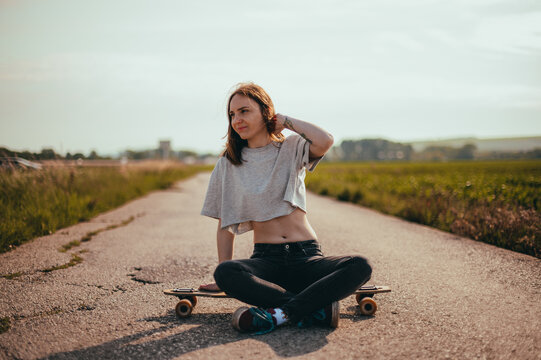 Portrait of a young pretty girl sitting on a longboard. lifestyle photo. woman riding a longboard