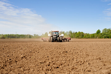 Fototapeta premium Sowing the land. Shot of a tractor seeding a large plowed field on a farm.