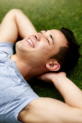 The outdoors bring a refreshing sense of calm. Shot of a handsome young man relaxing on the grass outdoors.