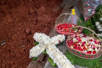 Cross bouquet on top a grave after burial ceremony