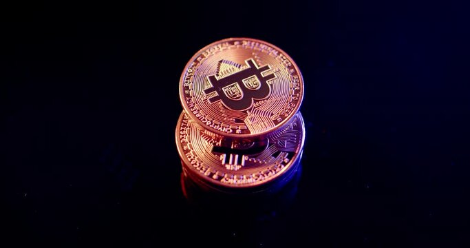 Gold Bitcoin coins on black surface spinning. Illuminated with golden light. Crypto currency coins concept of future economies