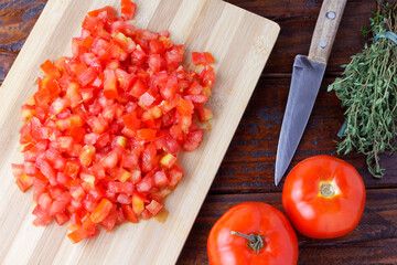 Raw chopped and diced tomatoes cubes over rustic wooden table