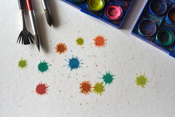 Paintbrushes with the color palettes and the color stains on the rough texture paper
