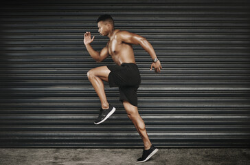 Obraz premium Feeling good and keeping fit. Shot of a fit and shirtless young man running.