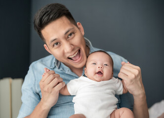 Happy Asian father spending quality time with his adorable baby girl at home